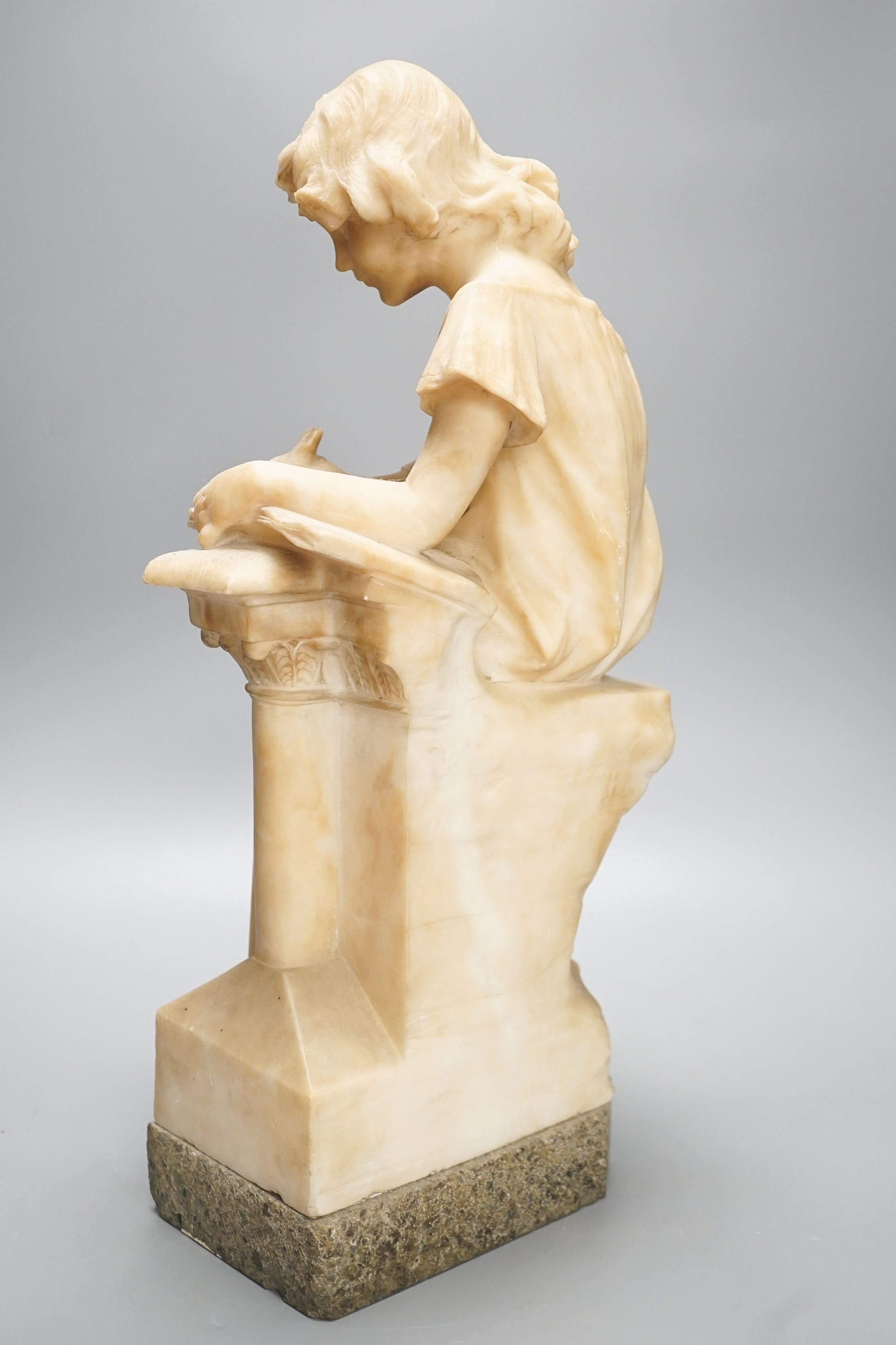 A late 19th century Italian carved alabaster figure of a girl seated, writing at a pillar 47cm